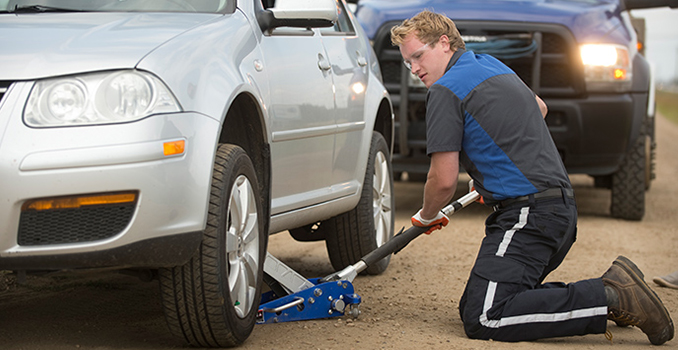 Emergency tire repair service fixing a flat tire on the roadside