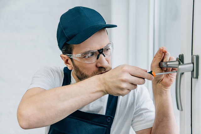 Locksmith repairing a door lock with a screwdriver.