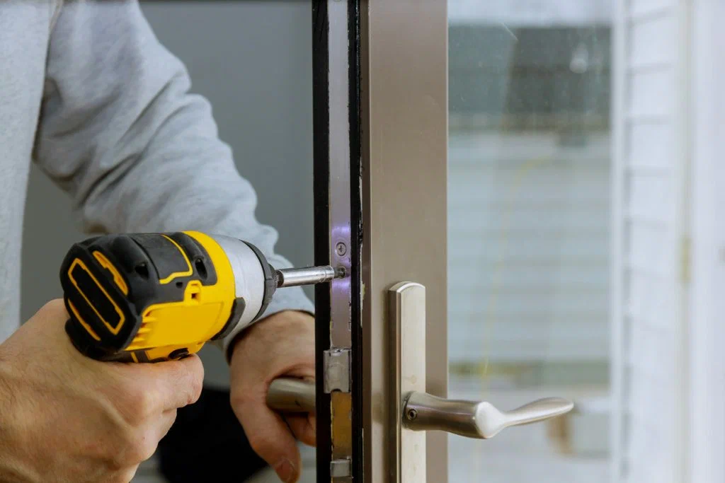 Person using a power drill to install or repair a door lock.