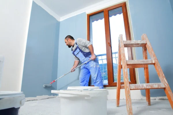 A painter painting a wall with a roller.